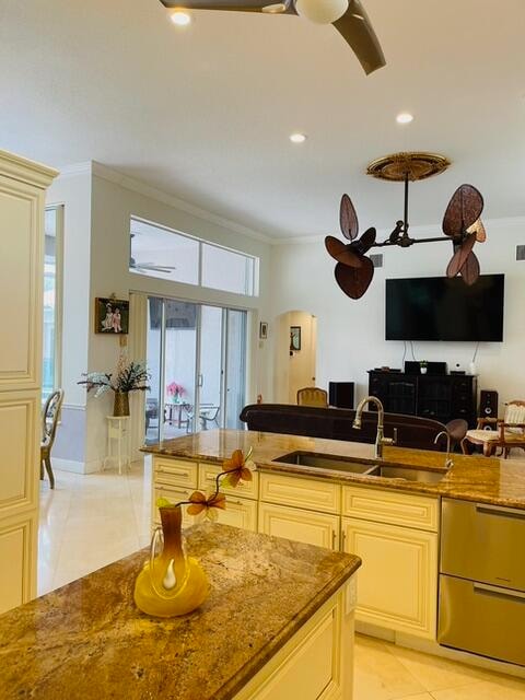 kitchen featuring light stone countertops, cream cabinets, pendant lighting, and sink