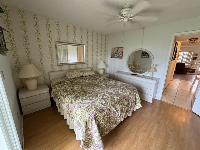 bedroom featuring light hardwood / wood-style floors, ceiling fan, and a textured ceiling