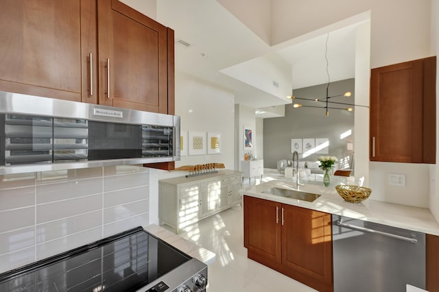 kitchen featuring sink, light stone countertops, a notable chandelier, light tile patterned flooring, and stainless steel appliances