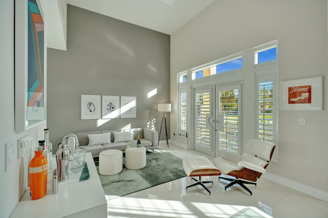 living room featuring french doors, light tile patterned floors, and a high ceiling