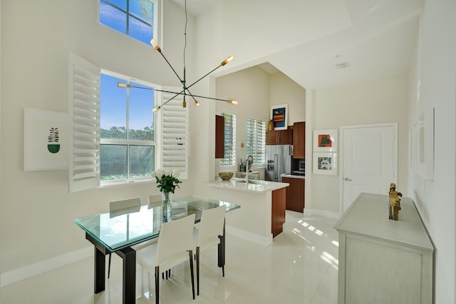 tiled dining space with a high ceiling and an inviting chandelier