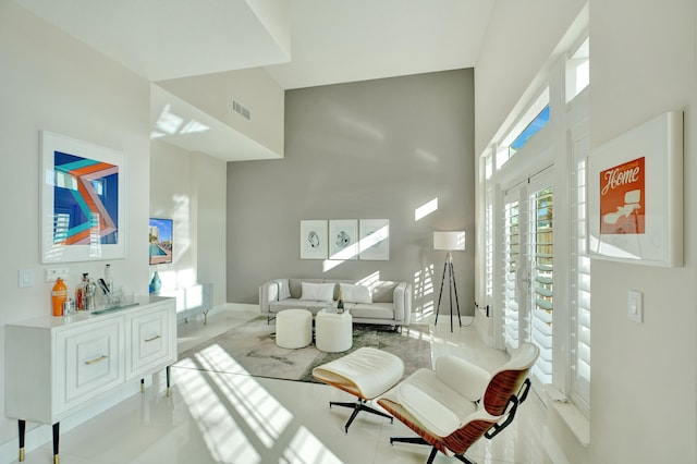 living room with a towering ceiling and light tile patterned flooring