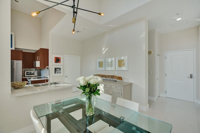 tiled dining area with sink and a high ceiling