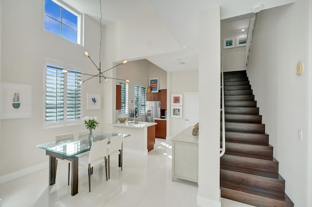 interior space featuring light tile patterned floors, a towering ceiling, and a notable chandelier