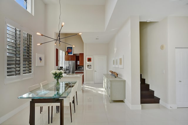 dining room featuring a towering ceiling, an inviting chandelier, and light tile patterned flooring