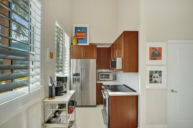 kitchen with light tile patterned flooring, backsplash, and appliances with stainless steel finishes