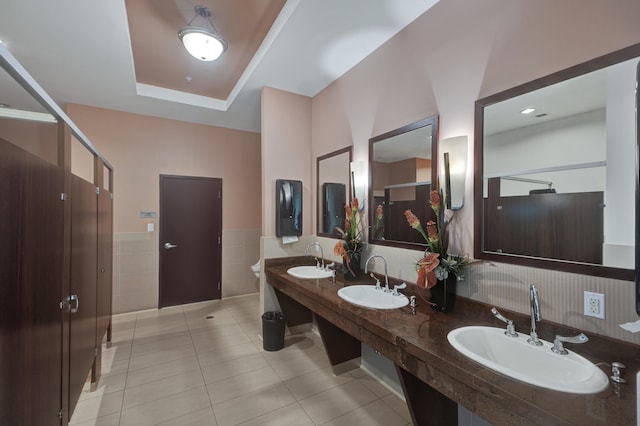 bathroom with tile patterned flooring, vanity, a raised ceiling, and tile walls