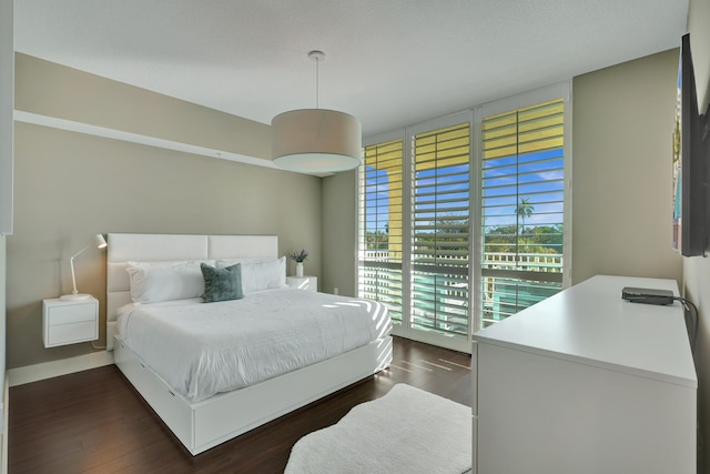 bedroom with access to exterior and dark wood-type flooring