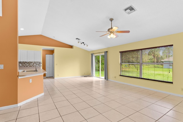 tiled spare room featuring track lighting, lofted ceiling, sink, and ceiling fan