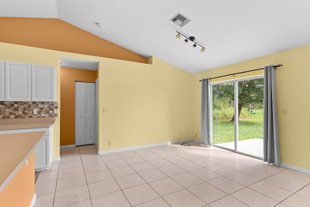 interior space featuring rail lighting, light tile patterned floors, and lofted ceiling