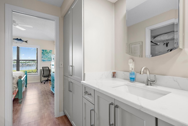 bathroom featuring ceiling fan, tile patterned flooring, vanity, and a textured ceiling