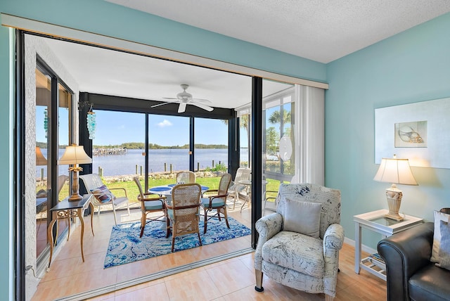 sunroom / solarium with ceiling fan and a water view