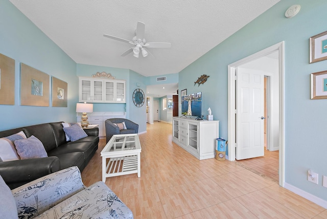 living room featuring ceiling fan, a textured ceiling, and light hardwood / wood-style flooring