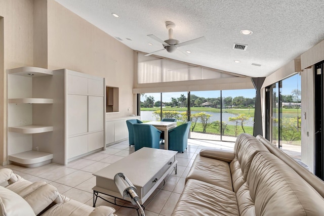 tiled living room with high vaulted ceiling, a water view, a textured ceiling, and ceiling fan