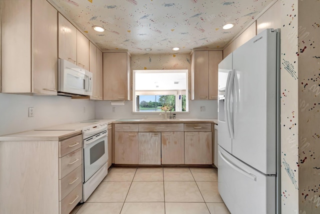 kitchen with light brown cabinets, light tile patterned floors, white appliances, and sink