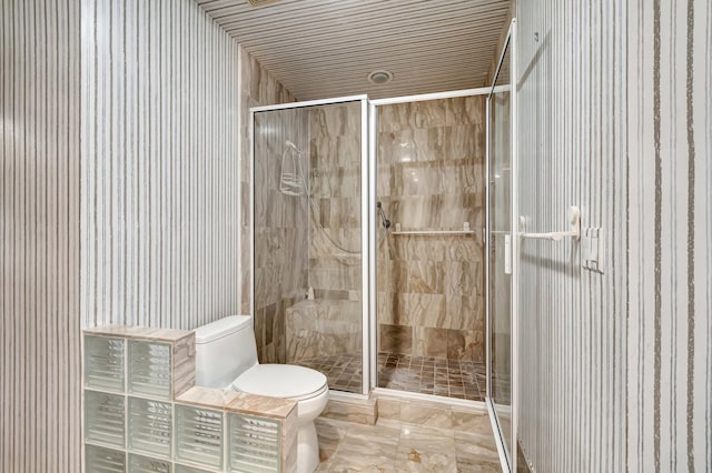 bathroom featuring a shower with door and toilet