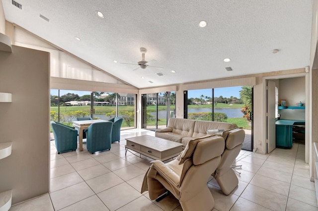 tiled living room with ceiling fan, a textured ceiling, a water view, and high vaulted ceiling