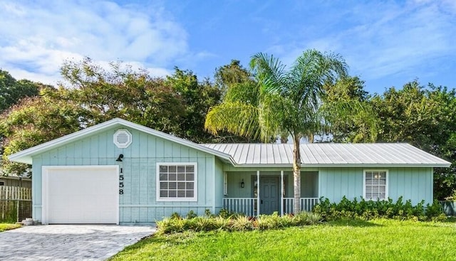 single story home with a porch, a garage, and a front yard