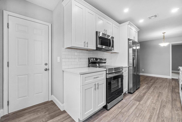 kitchen with white cabinets, decorative backsplash, stainless steel appliances, and hanging light fixtures