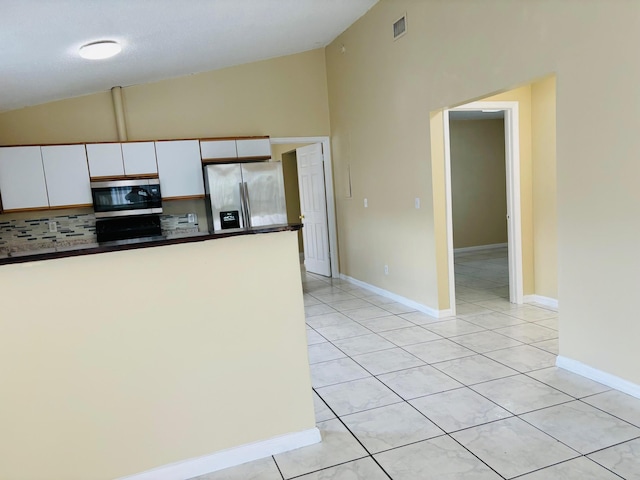 kitchen with light tile patterned flooring, white cabinetry, stainless steel appliances, and vaulted ceiling