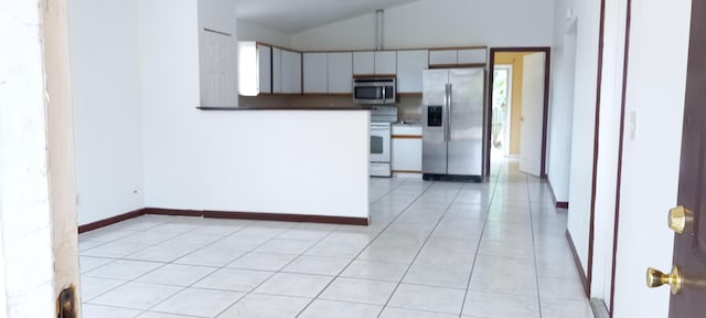 kitchen featuring white cabinetry, stainless steel appliances, light tile patterned floors, and vaulted ceiling