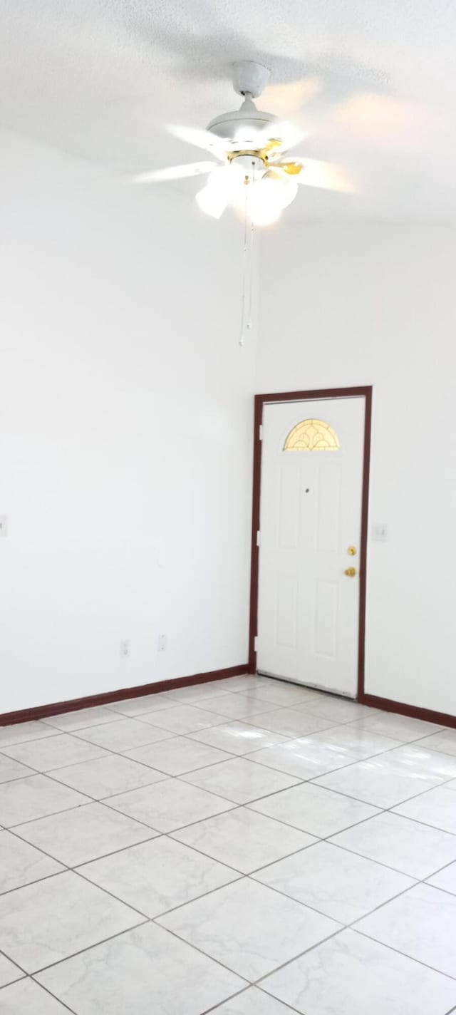 spare room featuring ceiling fan, light tile patterned floors, and a textured ceiling