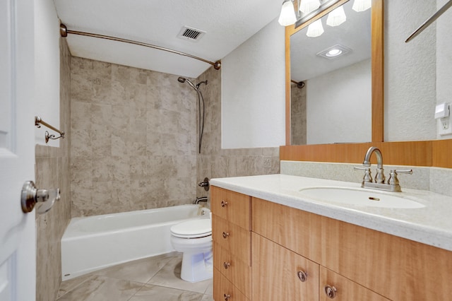 full bathroom with tiled shower / bath combo, a textured ceiling, toilet, vanity, and tile walls