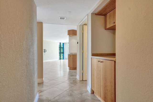 hall featuring light tile patterned floors and a textured ceiling