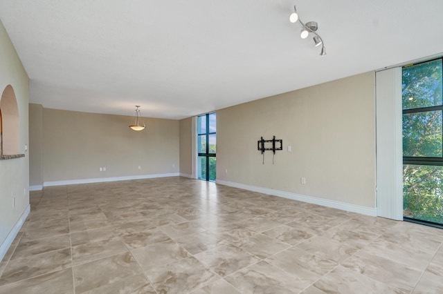 empty room with floor to ceiling windows and rail lighting