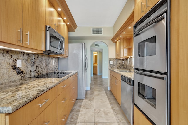 kitchen with light stone countertops, sink, stainless steel appliances, tasteful backsplash, and light tile patterned floors