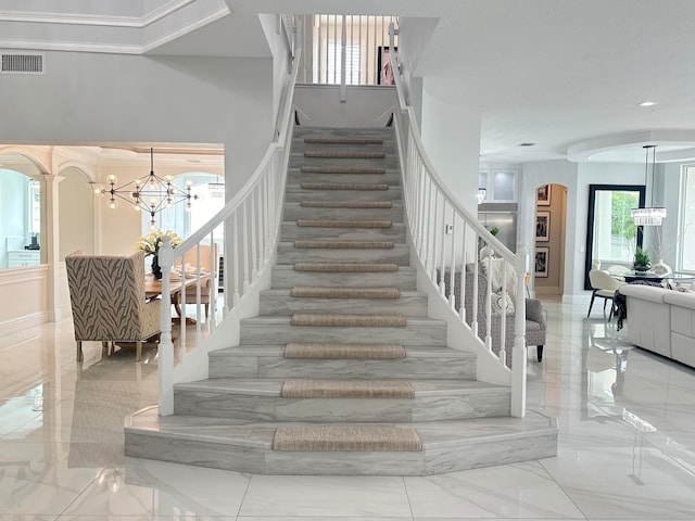 staircase with a notable chandelier and a towering ceiling