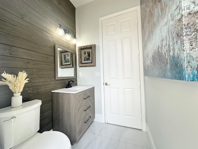 2727 Eleanor Way, Wellington, FL 33414 - bathroom featuring wood walls, marble finish floors, toilet, vanity, and baseboards