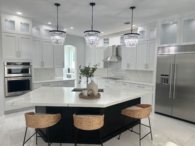 kitchen featuring a large island, white cabinetry, appliances with stainless steel finishes, and wall chimney exhaust hood