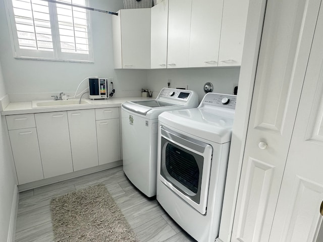 laundry room with independent washer and dryer, cabinets, and sink