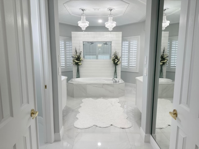 bathroom featuring a chandelier, a relaxing tiled tub, and plenty of natural light