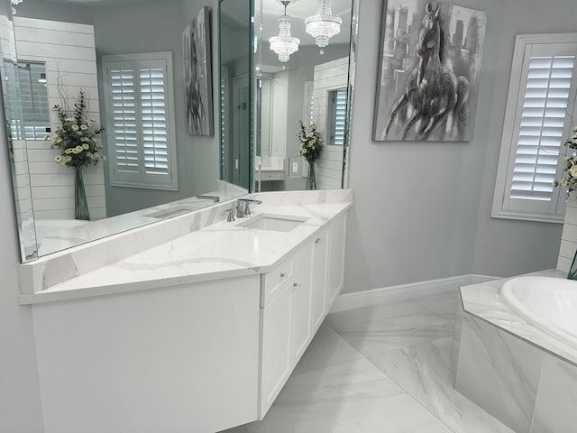 bathroom with a tub, vanity, and an inviting chandelier