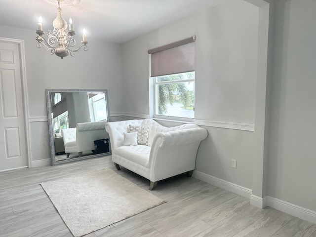 living area featuring a healthy amount of sunlight, light hardwood / wood-style flooring, and a notable chandelier