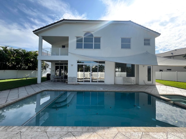 rear view of property featuring a swimming pool with hot tub and a patio