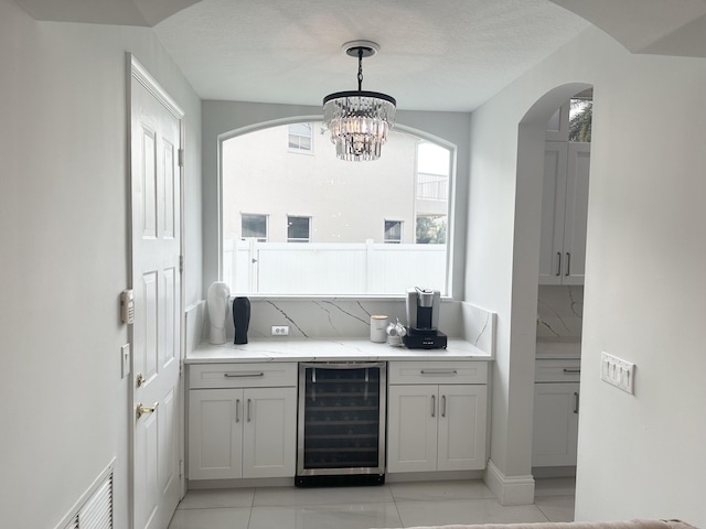 2727 Eleanor Way, Wellington, FL 33414 - bar with wine cooler, arched walkways, a chandelier, light tile patterned floors, and decorative light fixtures