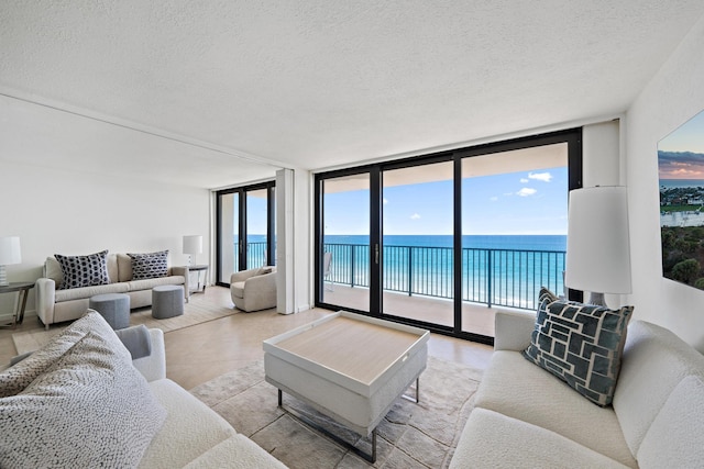 living area featuring a healthy amount of sunlight, a water view, floor to ceiling windows, and a textured ceiling