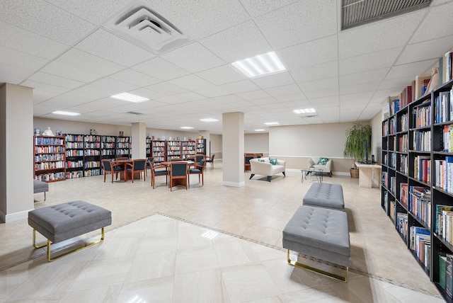 living area featuring tile patterned flooring, visible vents, and wall of books