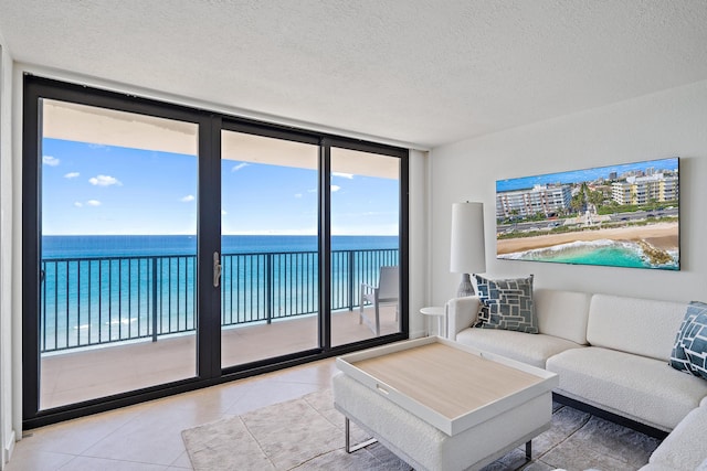 tiled living room with a textured ceiling, a water view, and floor to ceiling windows