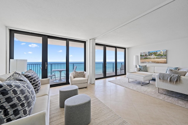 living area with a water view, light tile patterned floors, expansive windows, and a textured ceiling