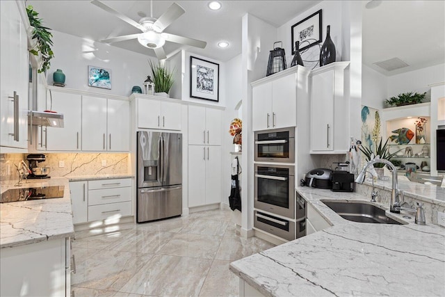 kitchen featuring appliances with stainless steel finishes, light stone counters, white cabinetry, and sink