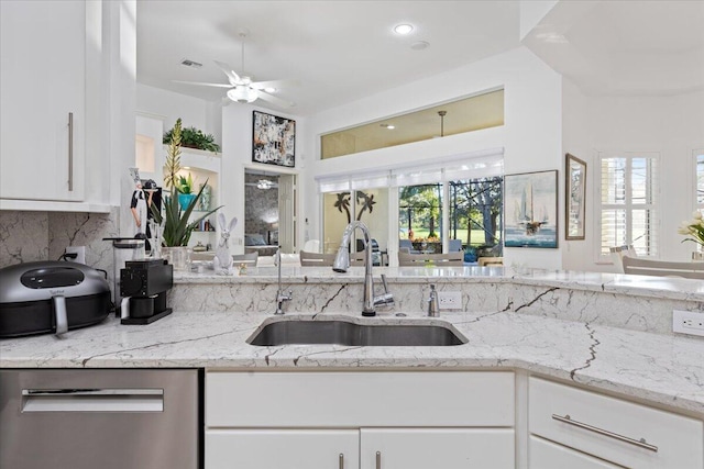 kitchen with light stone countertops, white cabinetry, sink, and a wealth of natural light