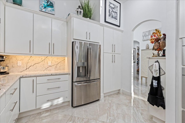 kitchen featuring tasteful backsplash, light stone countertops, white cabinets, and stainless steel refrigerator with ice dispenser