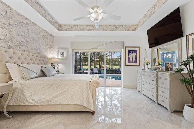 bedroom with a tray ceiling, access to exterior, ceiling fan, and multiple windows