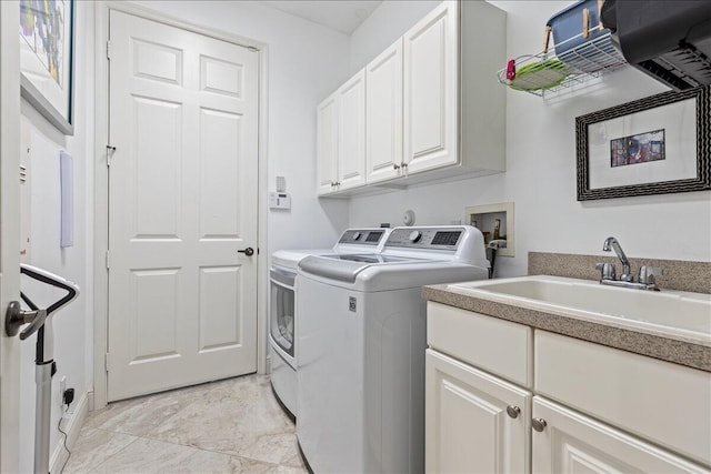 laundry room featuring washing machine and clothes dryer, cabinets, and sink