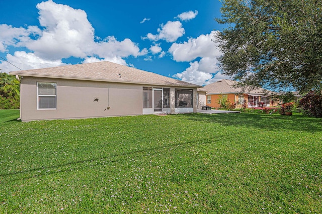 rear view of property featuring a sunroom and a lawn