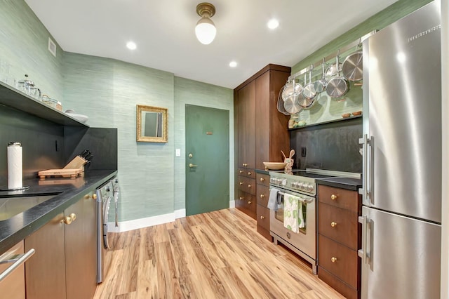 kitchen with stainless steel appliances, tile walls, and light hardwood / wood-style floors